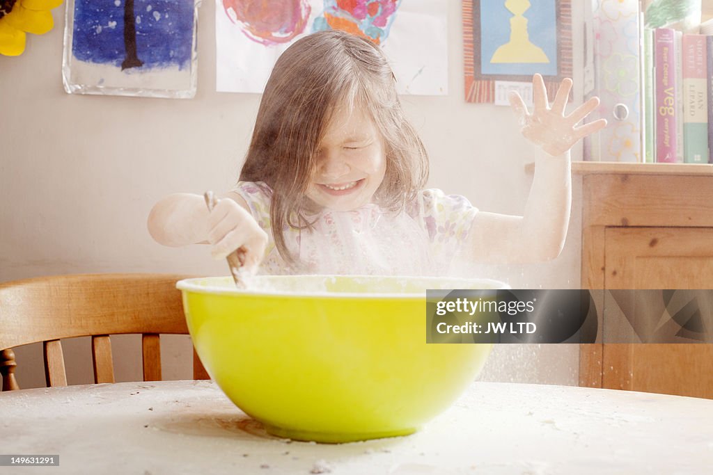 Girl (4-5) mixing flour in bowl