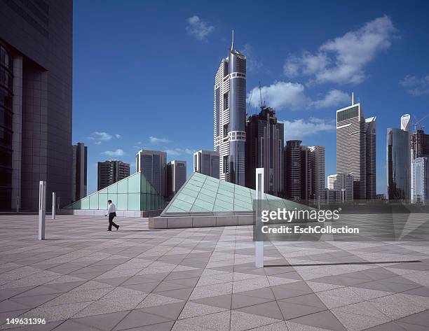 business man walking in office park in dubai - dubai buildings stockfoto's en -beelden