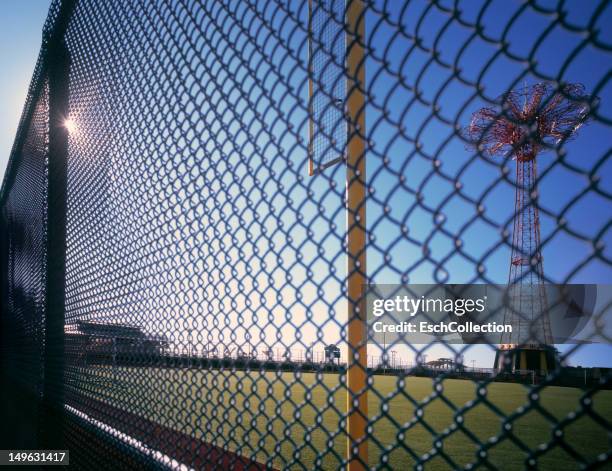 sunlight shining through fence at coney island - metal fence stock pictures, royalty-free photos & images