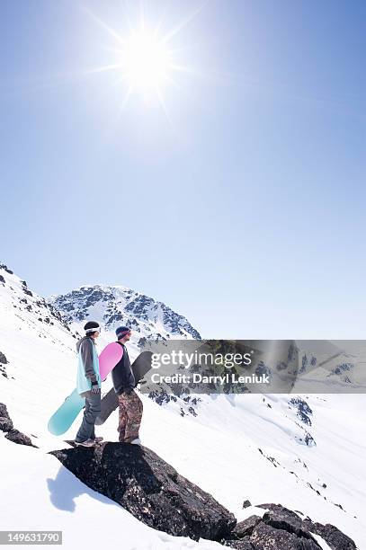 young snowboarders looking off into distance. - sun flare couple stockfoto's en -beelden