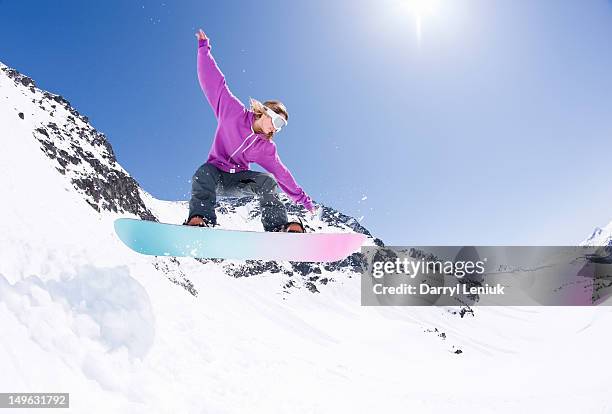 young female snowboarder jumping on snowboard. - snowboard jump bildbanksfoton och bilder