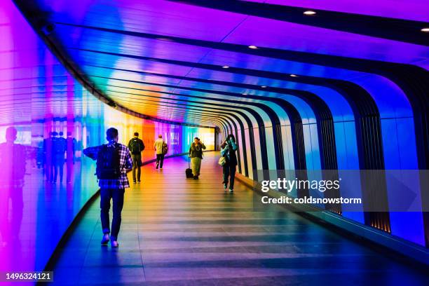 personas caminando a través de un túnel multicolor iluminado en londres, reino unido - estación de king's cross fotografías e imágenes de stock