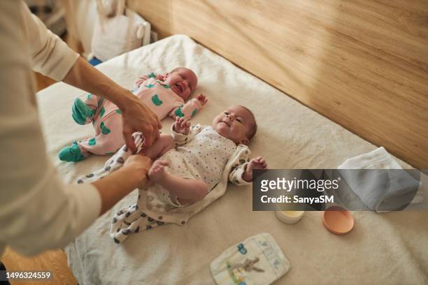 mother is taking care of newborn twin babies - tweeling stockfoto's en -beelden