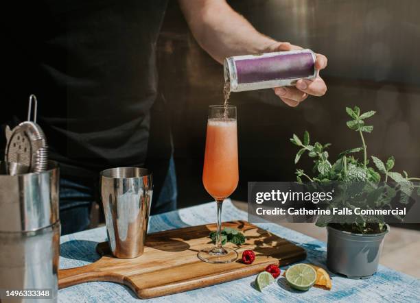 a mixologist creates a delicious blended drink, topping it off with a carbonated juice from a can. - cocktail party work stock pictures, royalty-free photos & images