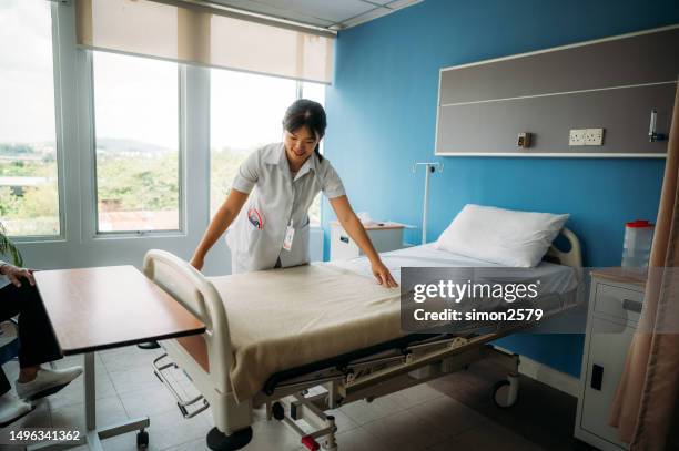 an asian female nurse making the bed at a hospital ward - make a change stock pictures, royalty-free photos & images