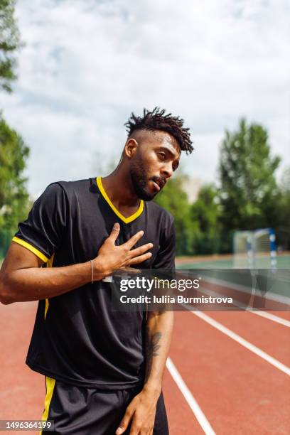 good-looking young man of west asian ethnicity standing on running track catching breath - west course stock pictures, royalty-free photos & images