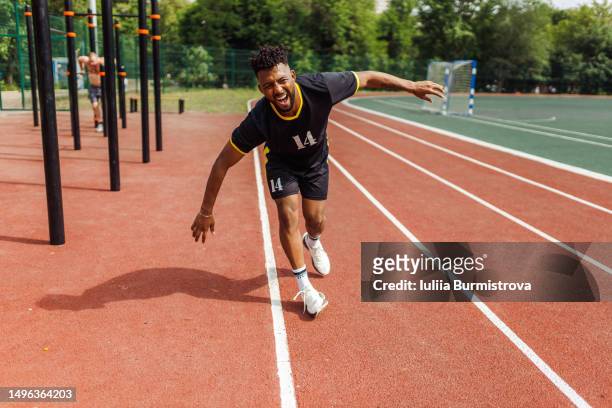 athletic arab male sports amateur walking on stadium track leaning forward feeling pain - tropeçar imagens e fotografias de stock