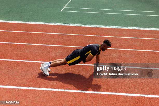 athletic young sportsman of west asian ethnicity doing shoulder taps in plank push-up position on running track - west course stock pictures, royalty-free photos & images