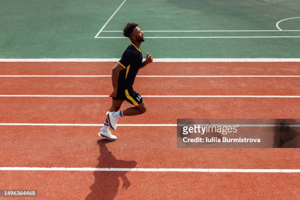 athletic iraqi man in soccer uniform running at college stadium - track and field stadium stockfoto's en -beelden