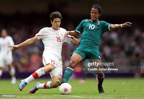 Giovani dos Santos of Mexico goes for the ball with Timm Klose of Switzerland during the Men's Football first round Group B match between Mexico and...