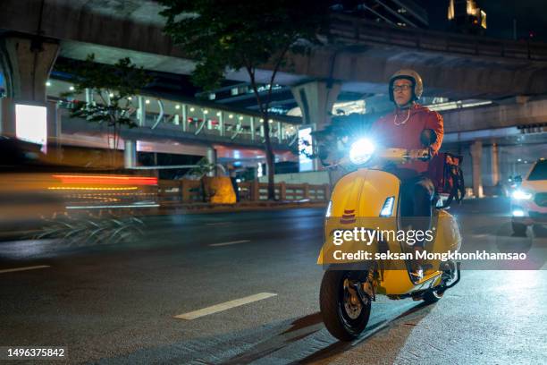 delivery man driving a scooter - motor scooter foto e immagini stock