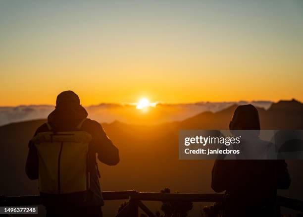 hikers watching a beautiful sunset over tall mountains - better view sunset stock pictures, royalty-free photos & images