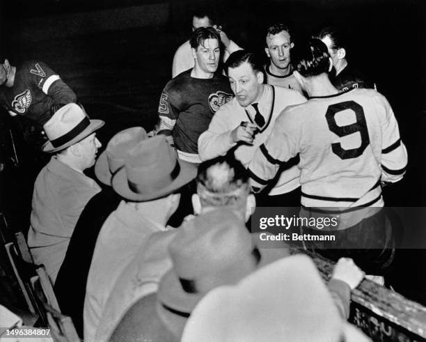 Referee Norman Lamport is surrounded by players as he remonstrates with spectators during the third game of the Stanley Cup between the Detroit Red...