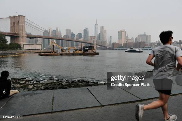 Person jogs through a Brooklyn park on a hazy morning resulting from Canadian wildfires on June 06, 2023 in New York City. Over 100 wildfires are...