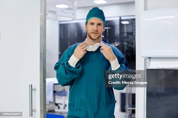 male surgeon removing mask at operating room - operatiegewaad stockfoto's en -beelden