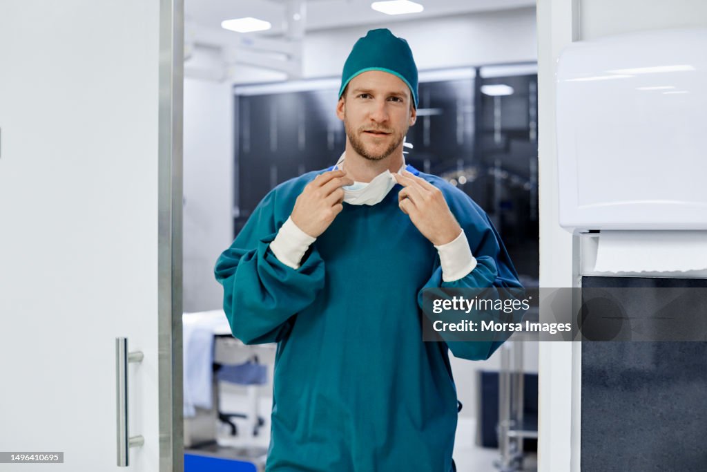 Male surgeon removing mask at operating room