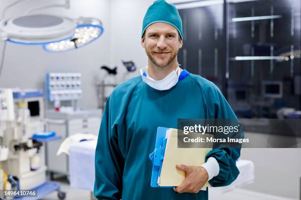 surgeon holding medical record in operating room - ropa de operar fotografías e imágenes de stock