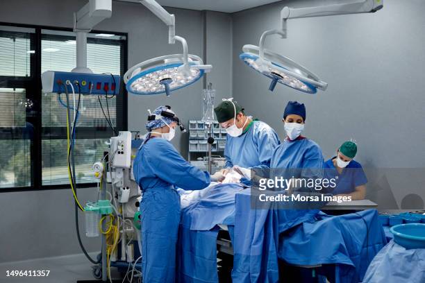 surgeons and doctors in illuminated operating room - operating room fotografías e imágenes de stock