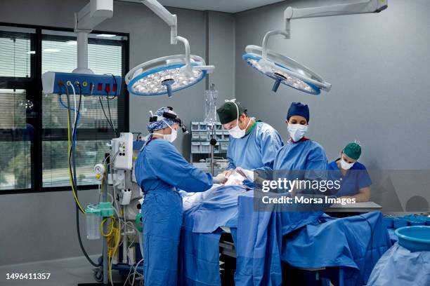 surgeons and doctors in illuminated operating room - sala de cirurgia com assistência imagens e fotografias de stock