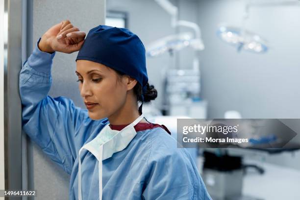 thoughtful surgeon with hand raised at hospital - surgical cap stock pictures, royalty-free photos & images