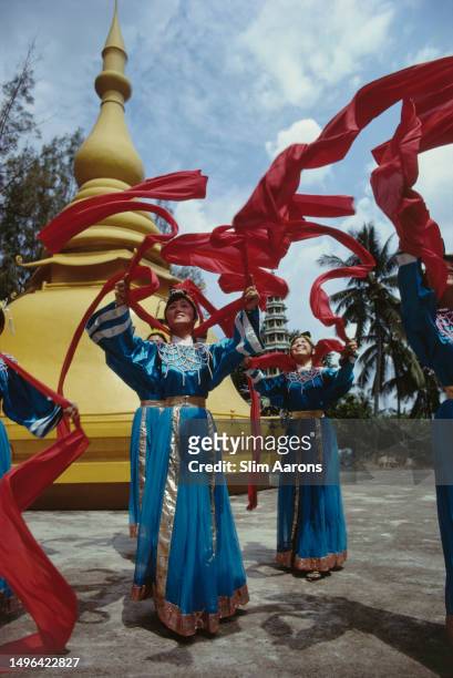 Women wearing traditional costume dancing with ribbons, Singapore, 1982.