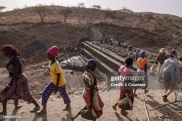 Community members from the city of Barentu carry bags of concrete mixture and rocks as members of the community complete a damn and reservoir project...