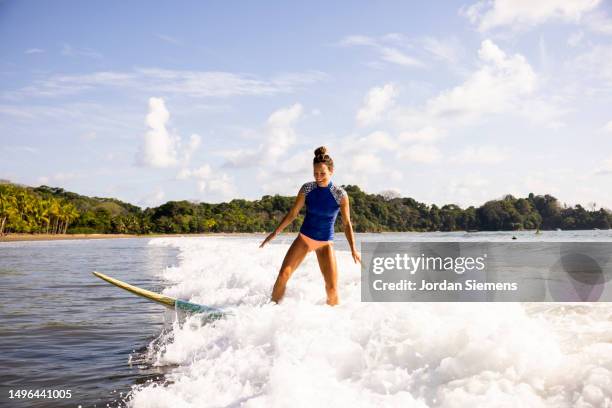 a woman catches a wave while surfing in costa rica. - san jose costa rica stock pictures, royalty-free photos & images