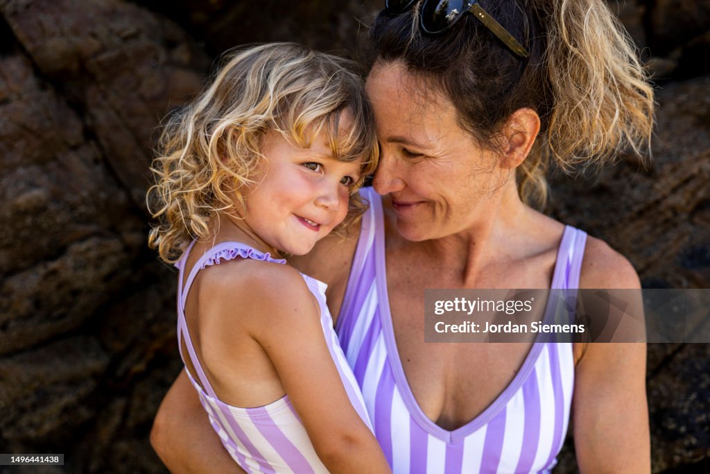 A mother holding her daughter in matching swim suites on a beach in Costa Rica.
