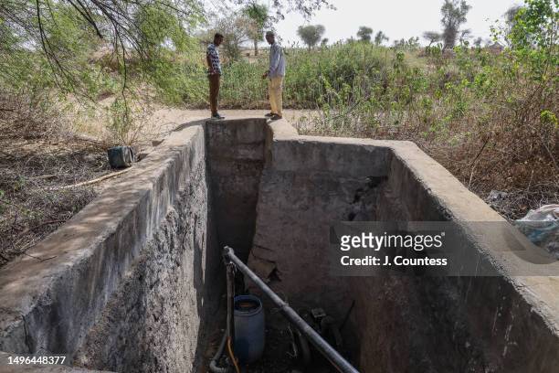 Communications Officer at the Ministry of Agriculture Andy Meskel Bererhe speaks with a local farmer as they stand over a water pumping station...