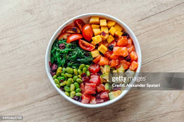 poke bowl with salmon, tuna and variety of fresh vegetables and fruits - kelp stock-fotos und bilder