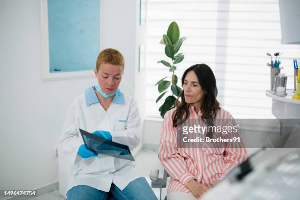 歯科医院で女性患者にx線画像を示す歯科医 - endodontist ストックフォトと画像