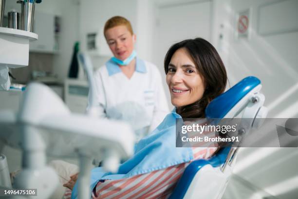 donna felice che visita un dentista per il trattamento dentale - adulto di mezza età foto e immagini stock