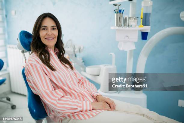 portrait of happy woman sitting in dental clinic looking at camera - patients brothers 個照片及圖片檔