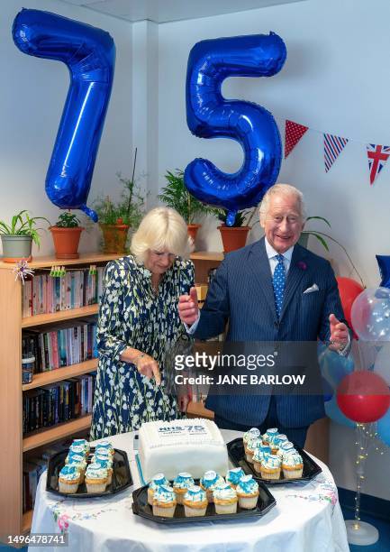 Britain's King Charles III and Queen Camilla cut a commemorative cake during a visit to NHS Lothian's Medicine of the Elderly Meaningful Activity...