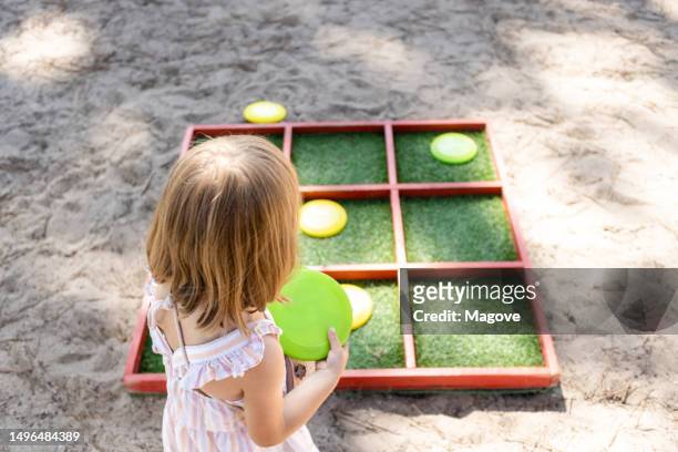 girl playing to put the puck in the hole, tic-tac-toe. - tic tac toe stock pictures, royalty-free photos & images