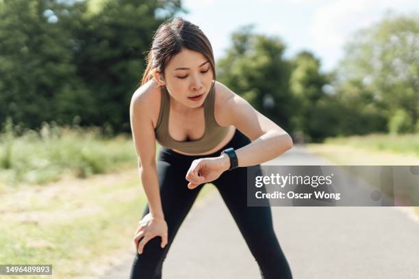 young asian woman tracking performance with fitness app on smartwatch after exercise - exercises stock pictures, royalty-free photos & images