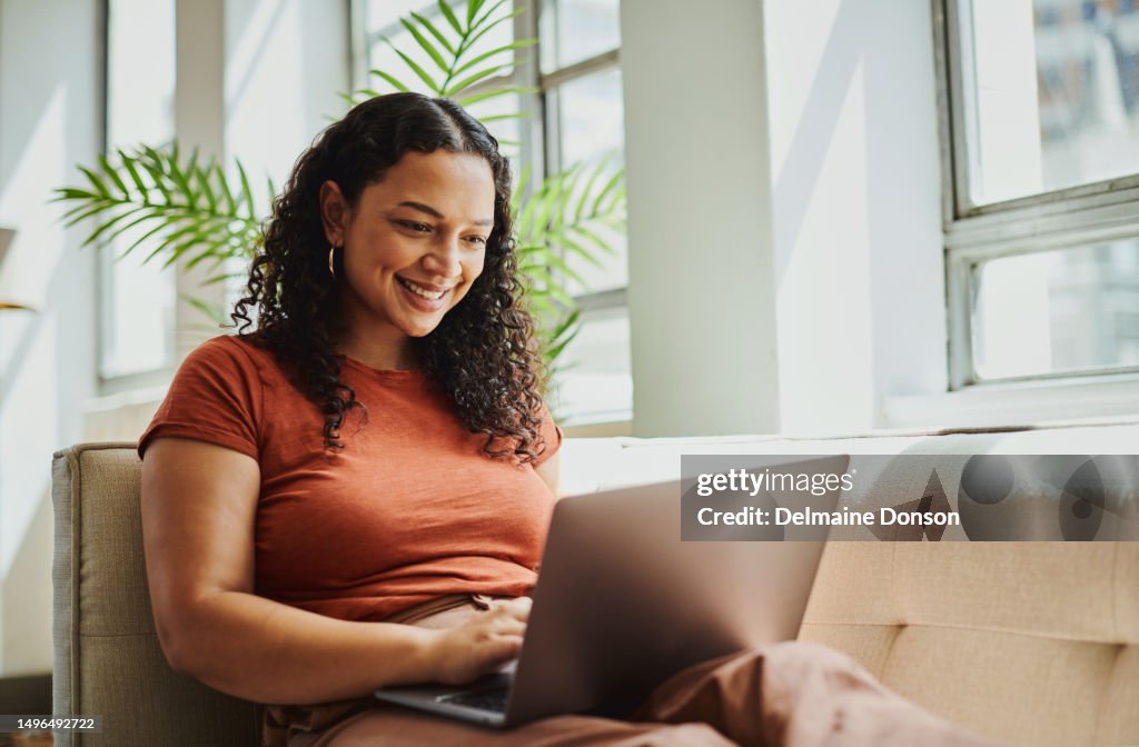 Shot of a young black woman sitting with her laptop computer, smiling with copy space. Stock photo