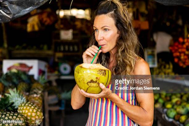 a woman drinking a fresh coconut from fruit stand in costa rica - costa rica women stockfoto's en -beelden