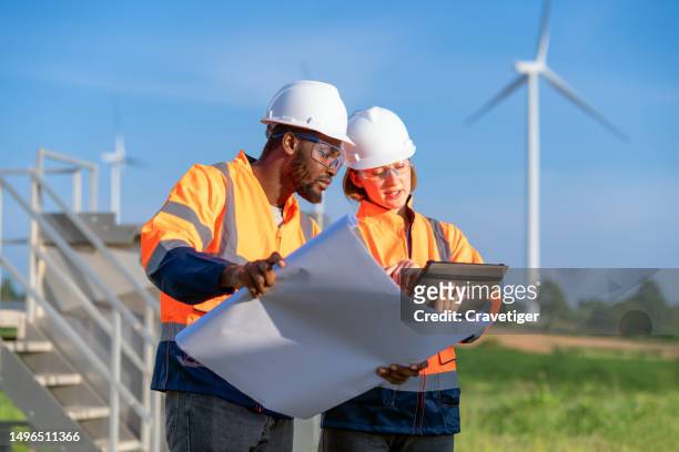 wind turbine engineers working on installation plans by drawing blueprints with coworkers in wind farms - - climate policy stock pictures, royalty-free photos & images