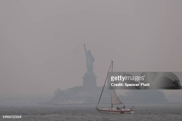 The Statue of Liberty stands shrouded in a reddish haze as a result of Canadian wildfires on June 06, 2023 in New York City. Over 100 wildfires are...