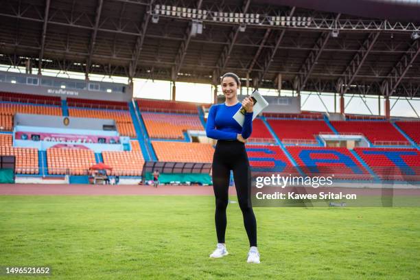 portrait of asian active sportswoman trainer stand outdoors on stadium. attractive strong athlete girl looking at camera after practice workout running marathon on the race for olympics competition. - olympiastadion rasen stock-fotos und bilder
