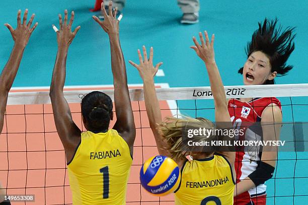 South Korea's Kim Yeon-Koung spikes as Brazil's Fabiana Claudino and Thaisa Menezes attempt to block during the Women's preliminary pool B volleyball...