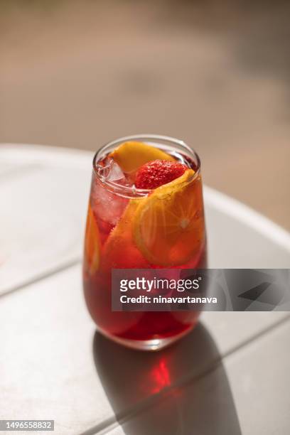 close-up of a summer cocktail with slices of orange and strawberries on a table - aperol stock pictures, royalty-free photos & images