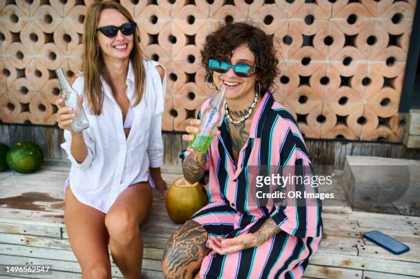 two happy female friends with cool drinks on patio - 2 coconut drinks ストックフォトと画像