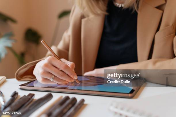 close-up of an illustrator sitting at a table drawing a donut on a graphic tablet - illustrator imagens e fotografias de stock