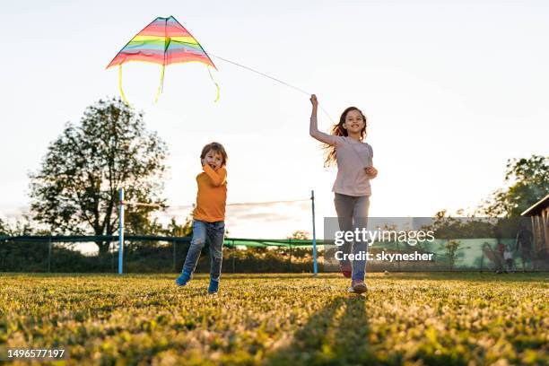 bambini piccoli spensierati che corrono con un aquilone nel cortile. - innocenza foto e immagini stock