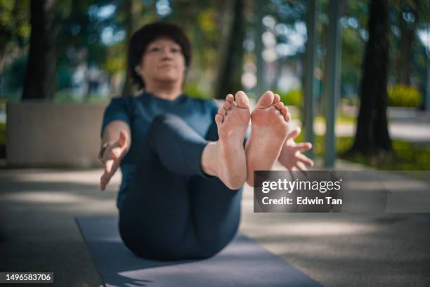 asiatische chinesische reife frau, die yoga im öffentlichen park am wochenendmorgen praktiziert - spirituelle erleuchtung stock-fotos und bilder