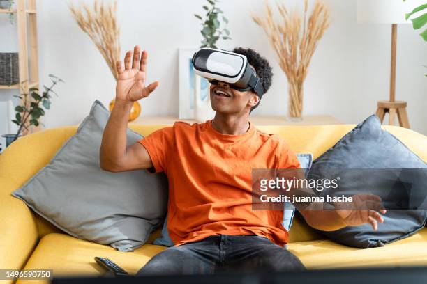 man playing vr game at home - lunettes de pilote de course photos et images de collection