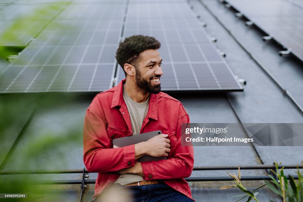Young man with digital tablet on the roof with solar panels.