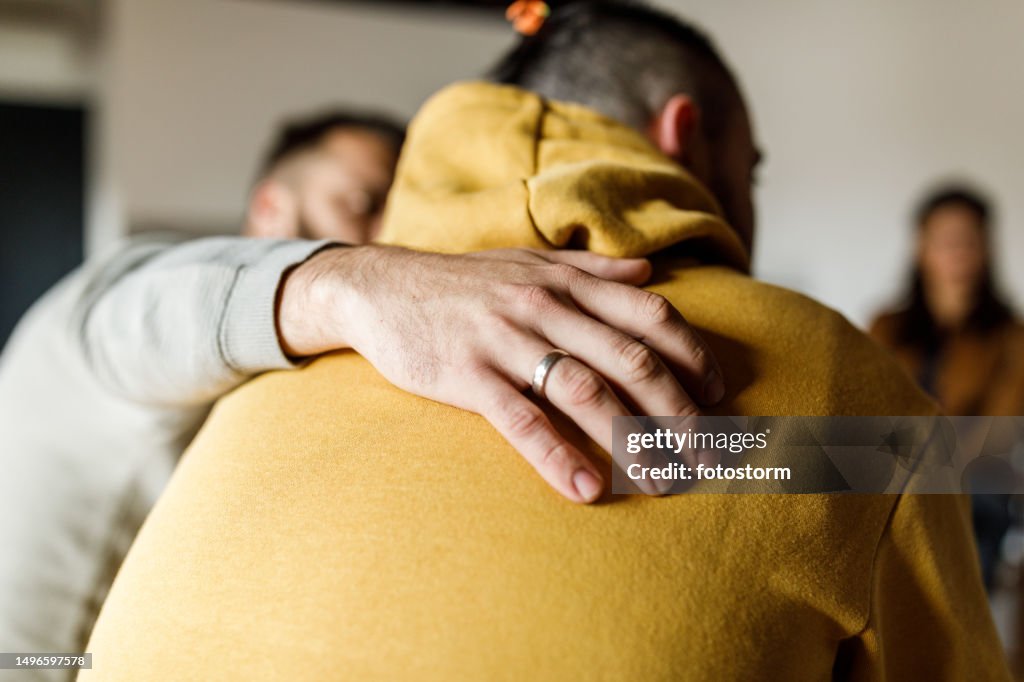 Man embracing his friend who is sharing his story at the group therapy session